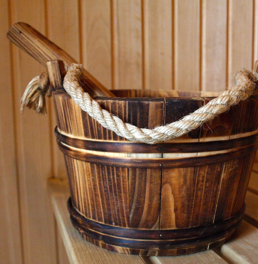 Wooden watr bucket with rope handle and ladel on sauna bench